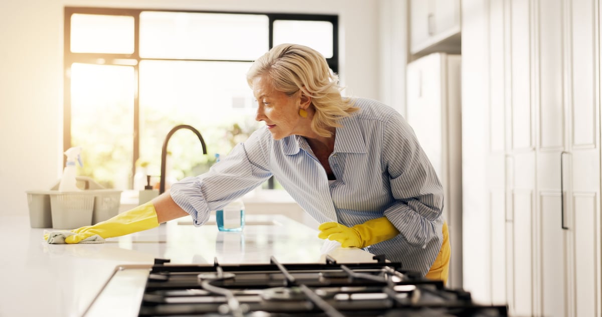 Mature woman, cloth and cleaning kitchen counter in home for hygiene